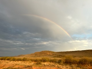 Solitude and silence as seen by a rainbow in the sky over foothills.